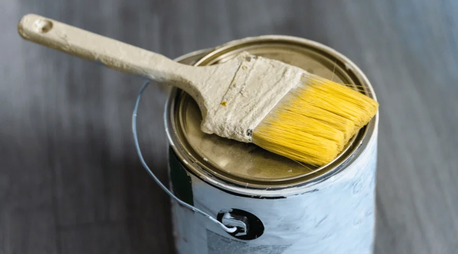 old paint brush on top of a closed paint can